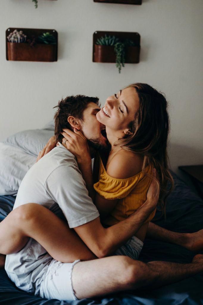 a man and woman cuddle on top of each other in the middle of a bed