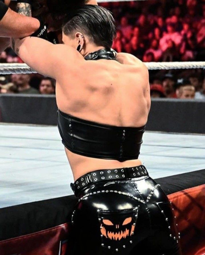 a woman in black leather pants and a wrestling ring