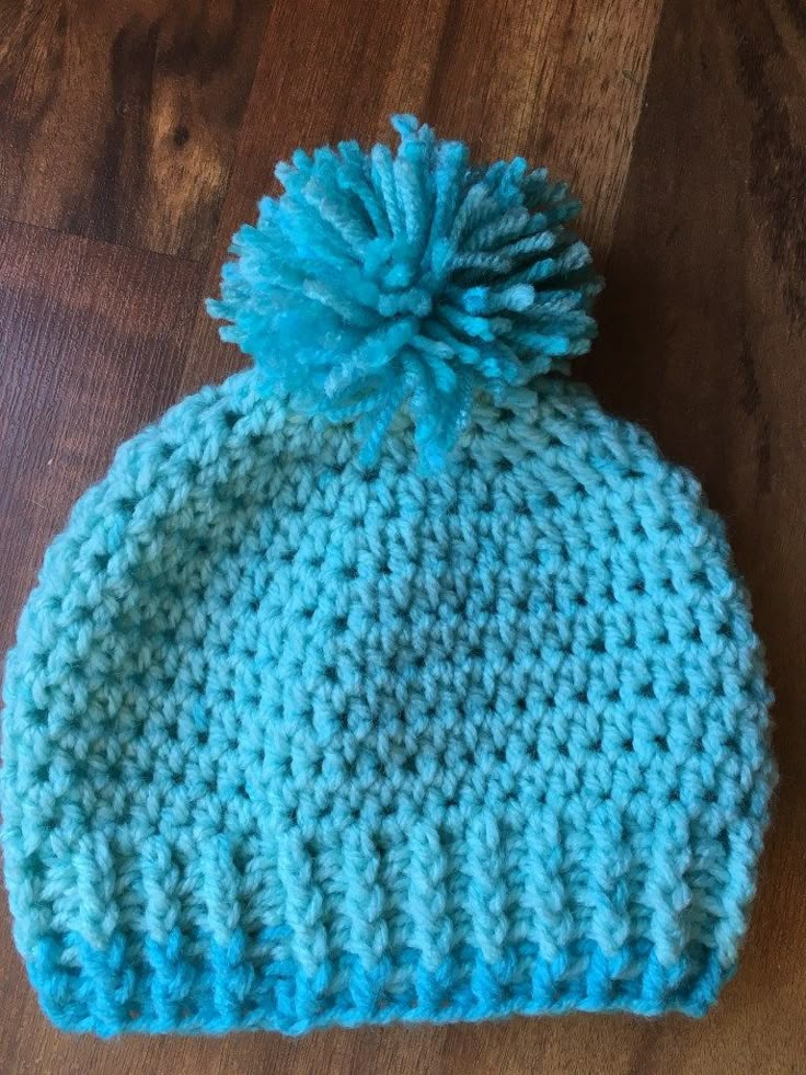 a-crocheted-hat-with-a-blue-pom-pom