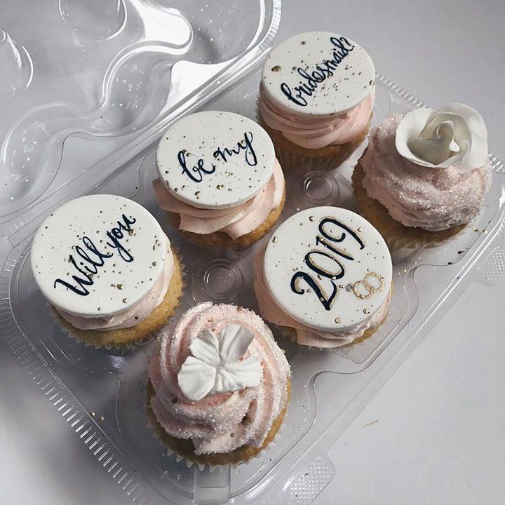 six cupcakes in a plastic container with writing on them