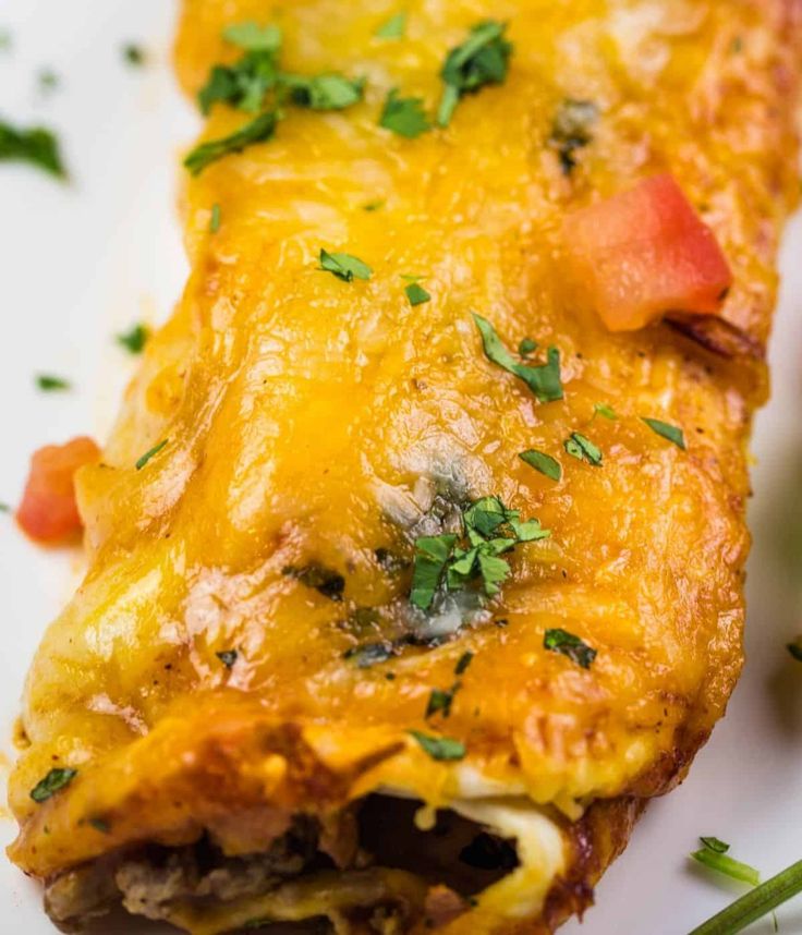 Cheesy beef enchilada topped with cheese, tomatoes, and fresh cilantro ...