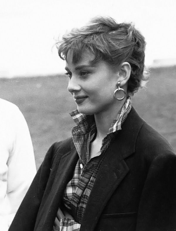 a black and white photo of a woman wearing earring's in front of a man