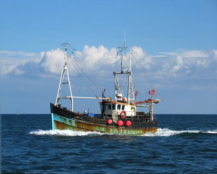 an old rusted fishing boat in the middle of the ocean on a sunny day