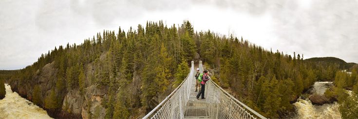 two people are walking across a suspension bridge