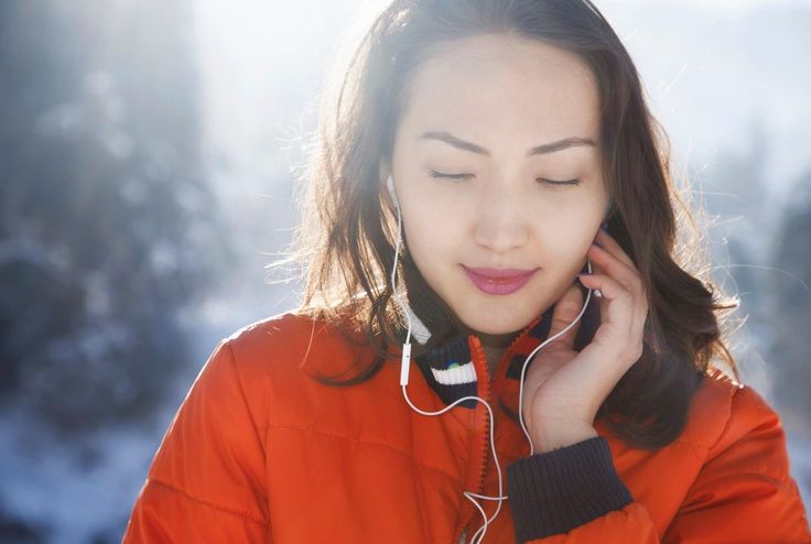 A Woman In An Orange Jacket Is Talking On Her Cell Phone And Listening a-woman-in-an-orange-jacket-is-talking-on-her-cell-phone-and-listening