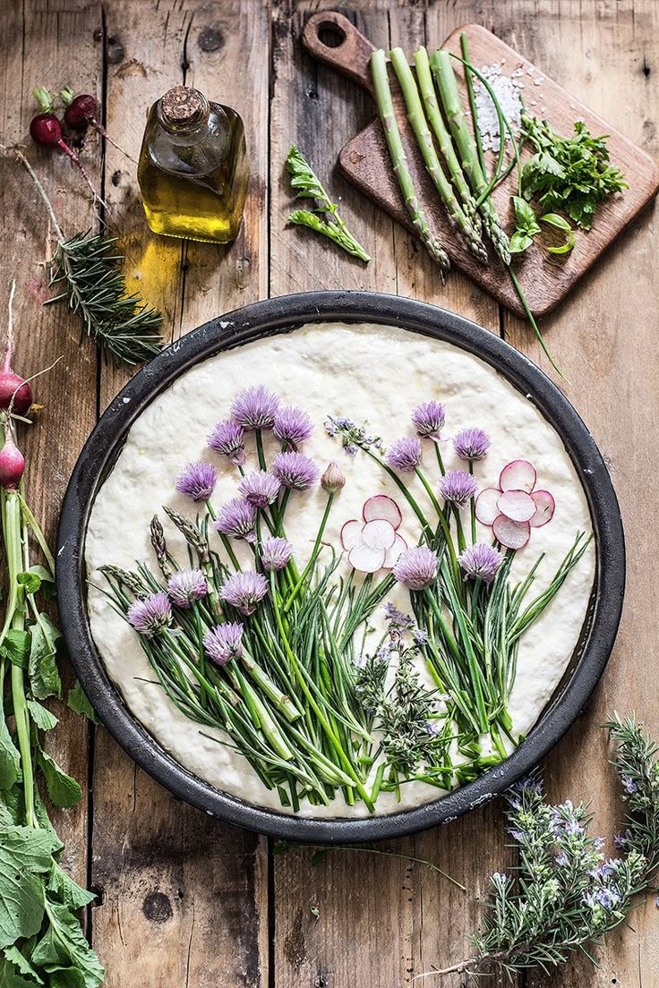 an assortment of vegetables are laid out on a wooden table next to a pizza crust