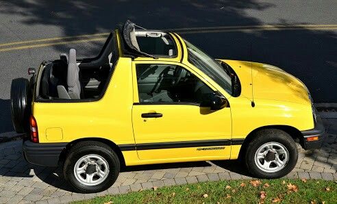 a small yellow truck parked on the side of the road