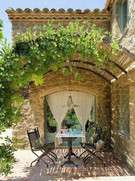 Arched pergola over stone farmhouse patio dining area. Romantic French Country G...