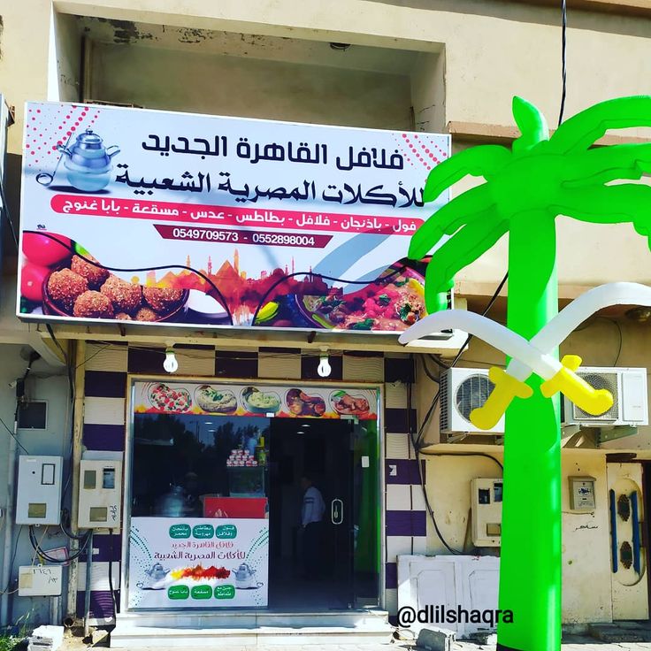 an advertisement on the side of a building in front of a palm tree and telephone booth