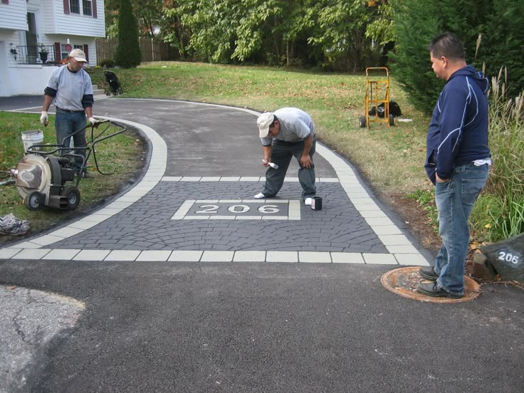 two men are working on an asphalt driveway