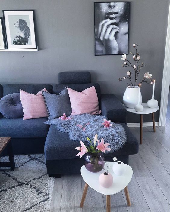 a living room with grey walls and pink pillows on the couch, white coffee table