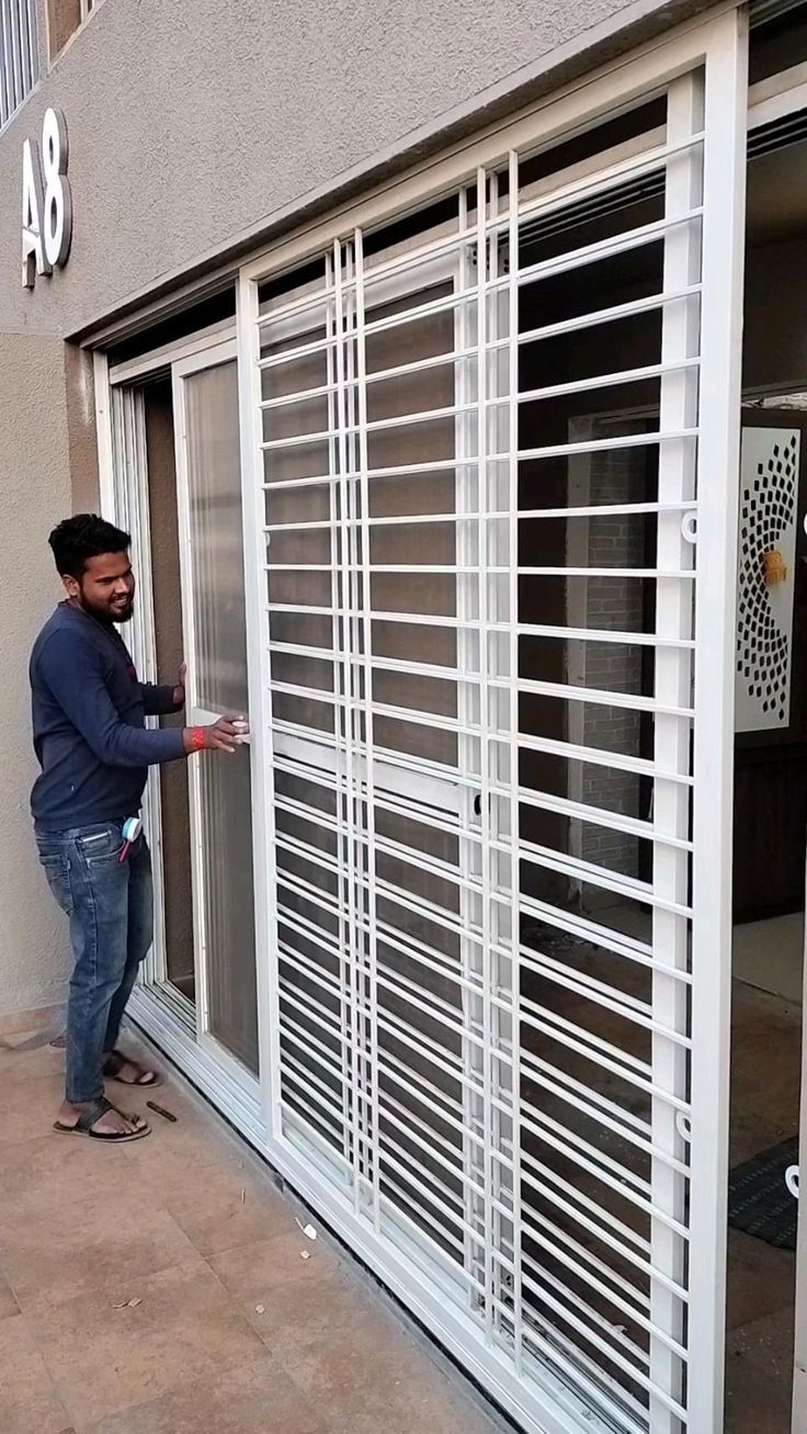 This may contain: a man standing in front of a sliding glass door with his hand on the side