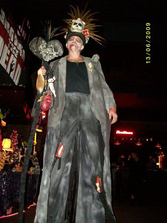 a man dressed in costume standing next to a sign a man dressed in costume standing next to a sign