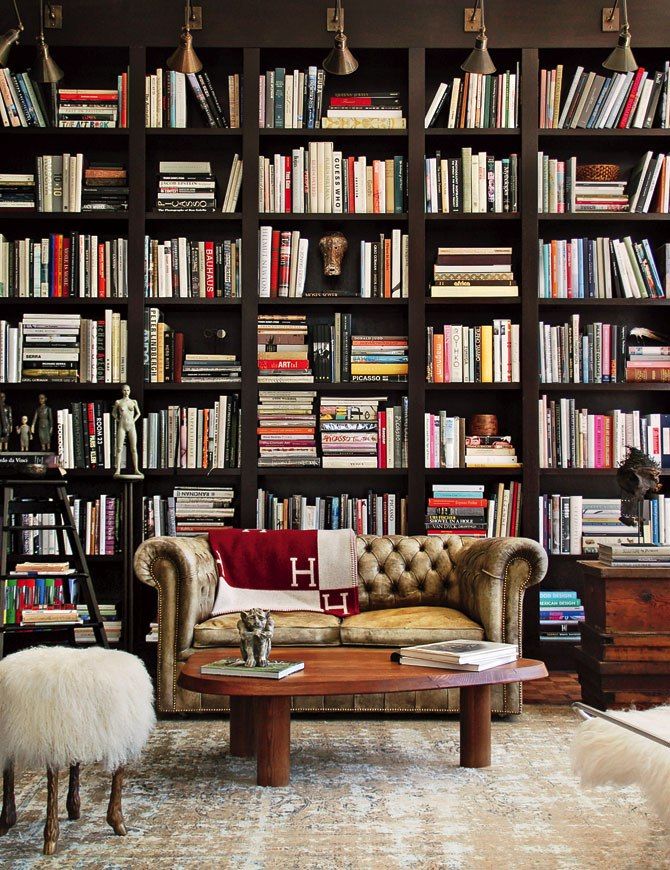 a living room filled with lots of books on top of a book shelf next to a couch