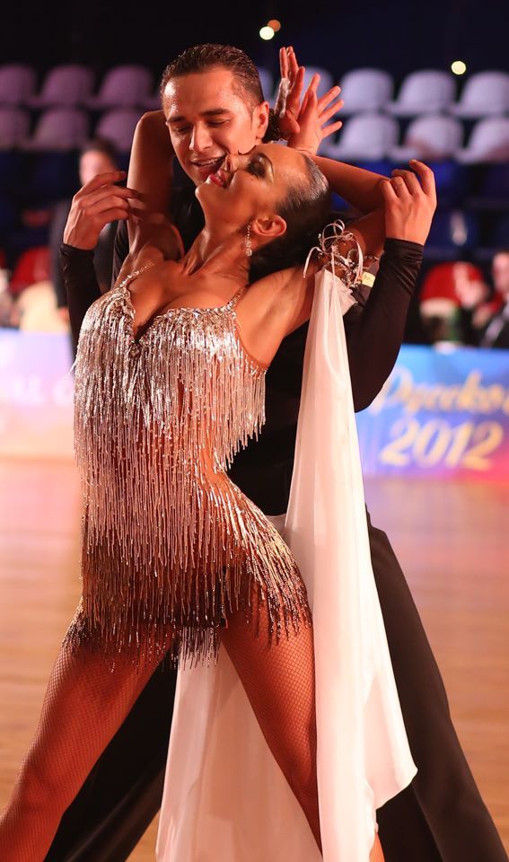 two people dancing on a dance floor with one holding the other's arm around his neck