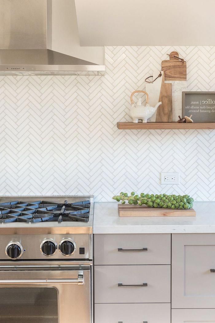 Herringbone Backsplash In White With Cream Colored Joints Near A Metal Extr Farmhouse Kitchen Tiles Designs Kitchen Backsplash Designs