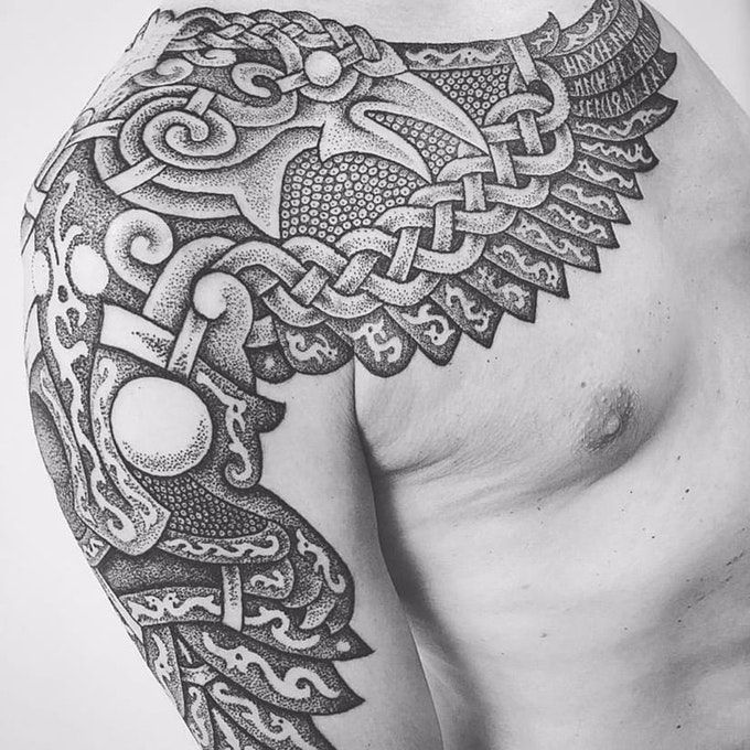 a black and white photo of a man's arm with an intricate tattoo design on it