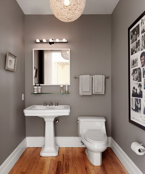 a white toilet sitting next to a sink in a bathroom under a round light fixture