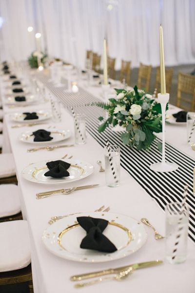 the table is set up with black and white place settings for guests to sit at