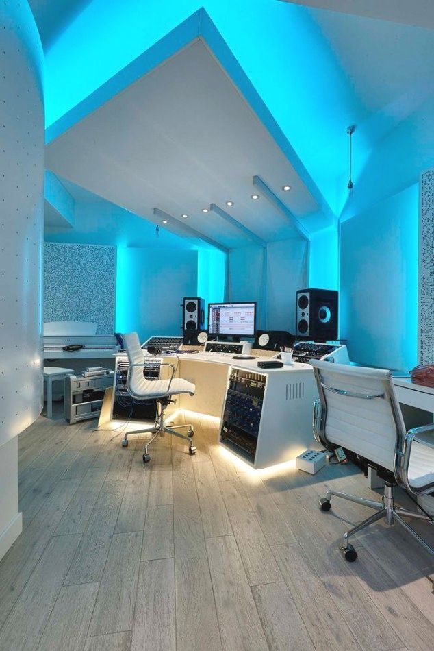 an office with blue lighting and desks in the center, along with two computer monitors