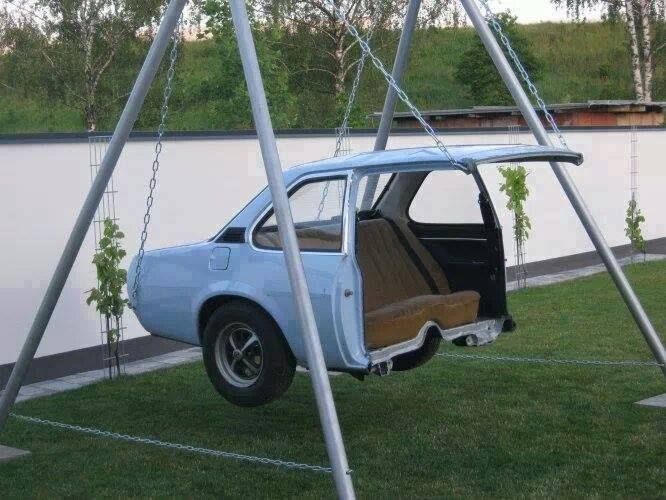 an old car is parked under a swing set