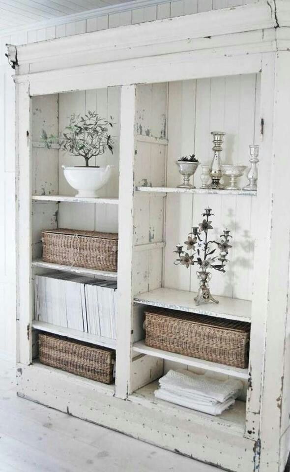 an old white bookcase with wicker baskets and flowers in it is displayed on the wall