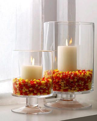 Fill hurricanes one third full with candy corn and nestle white pillar candles i...