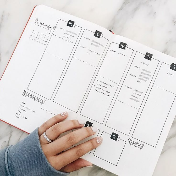 a woman's hand is holding a planner on top of a marble countertop