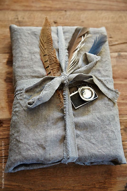 Hipster gift wrapped in linen with feathers and vintage camera on wood surface
