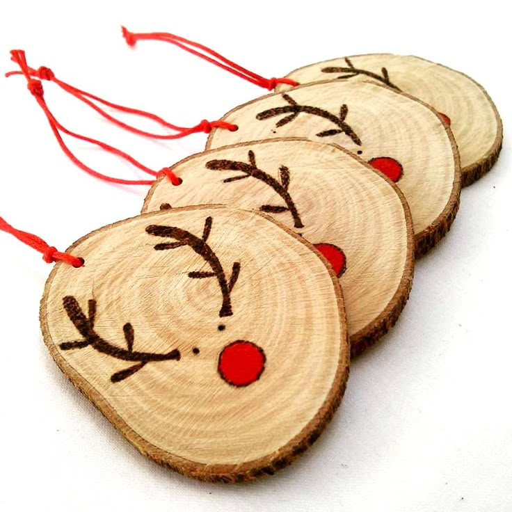 three wooden ornaments with reindeer faces on them, hanging from red string in front of an instagram page