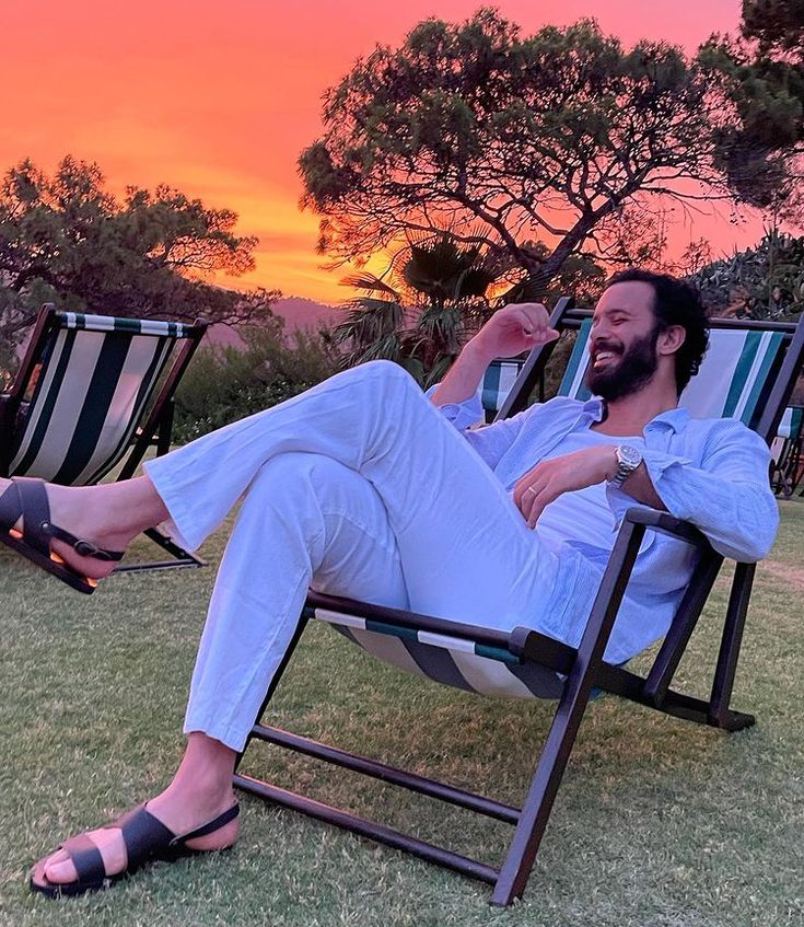 A Man Sitting In A Lawn Chair With His Feet On The Ground And Arms Crossed a-man-sitting-in-a-lawn-chair-with-his-feet-on-the-ground-and-arms-crossed