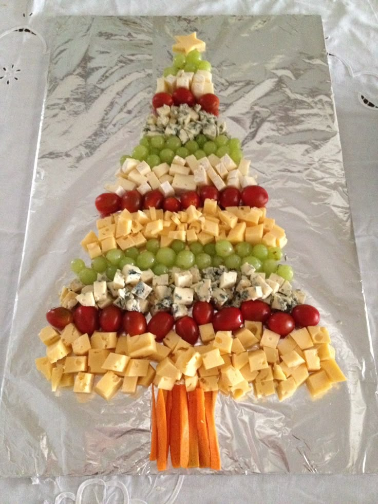 a christmas tree made out of cheese and crackers is displayed on a sheet of aluminum foil