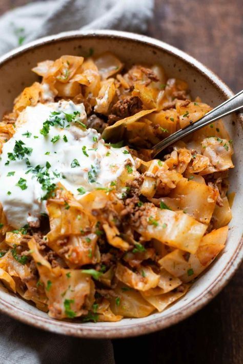 a bowl filled with pasta, meat and sour cream on top of a wooden table