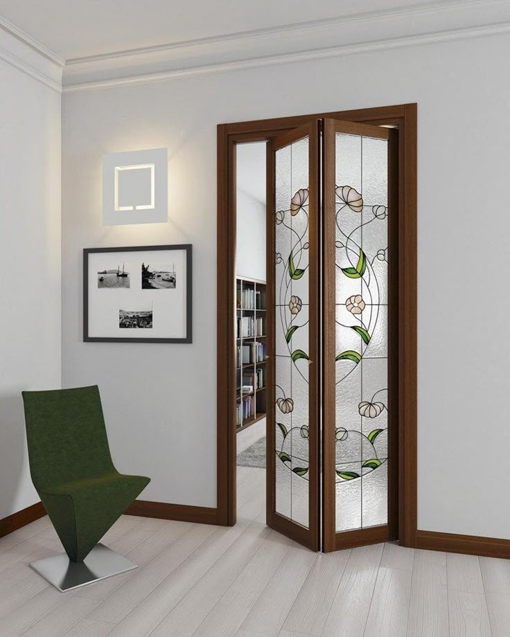 an open glass door in a room with a green chair and pictures on the wall