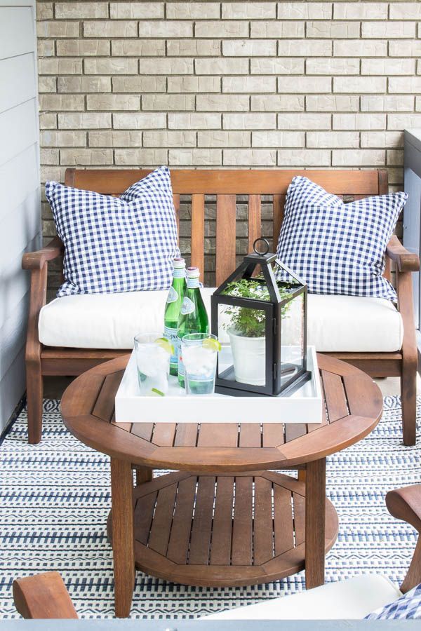 a wooden bench sitting on top of a patio next to a table with bottles and glasses