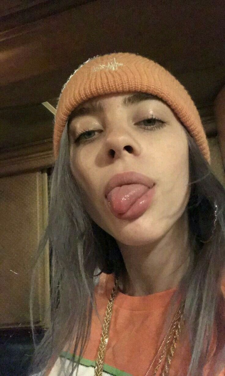 a woman sticking her tongue out while wearing an orange hat