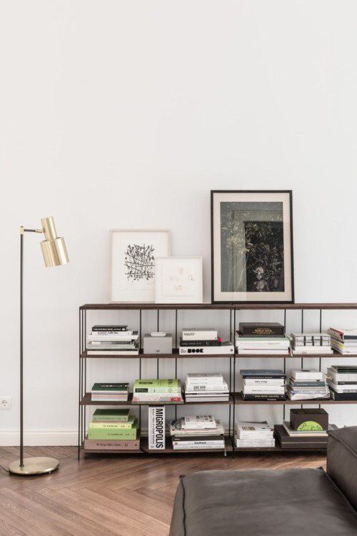 a bookshelf filled with lots of books next to a lamp and pictures on the wall