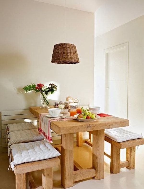 a dining room table with two benches and a basket hanging from the ceiling over it