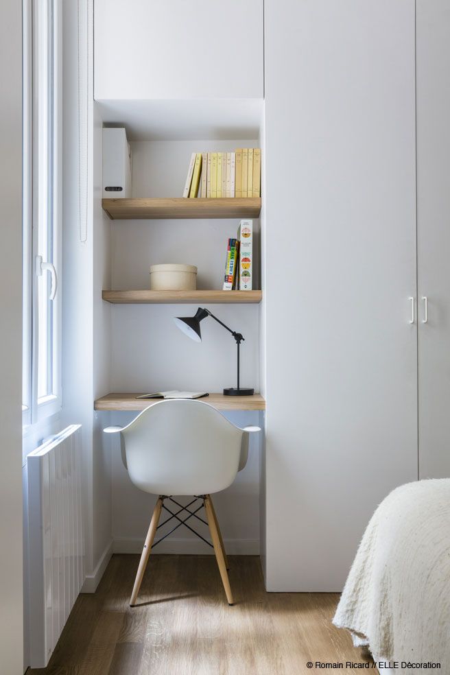 a bedroom with white walls and wooden flooring, built in bookshelves to the side