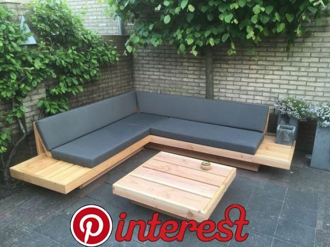 a couch and coffee table sitting in front of a brick wall next to a tree