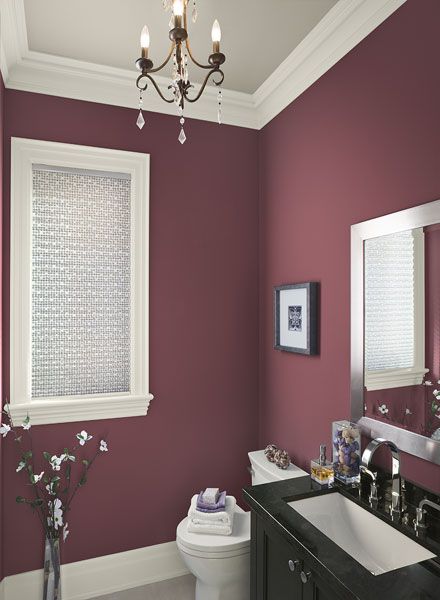 a bathroom with pink walls and white trim on the ceiling, along with a black vanity