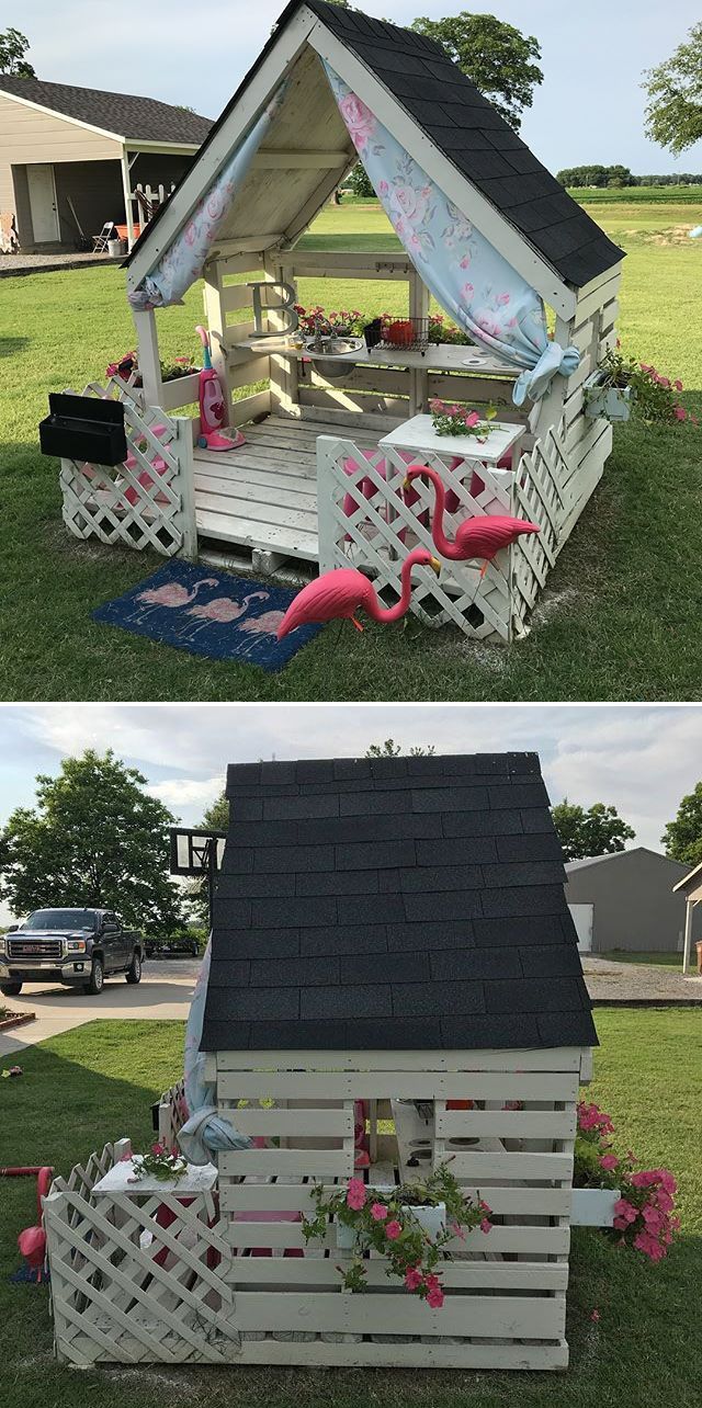 a small house made out of wooden pallets with flowers and umbrellas on the roof