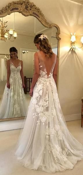 a woman in a wedding dress looking at herself in the mirror with her back to the camera