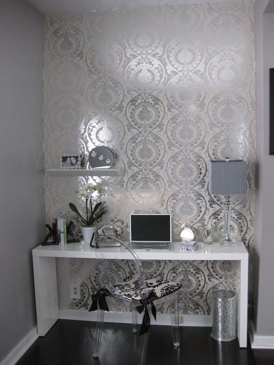 a white table with a laptop on top of it in front of a wallpapered background