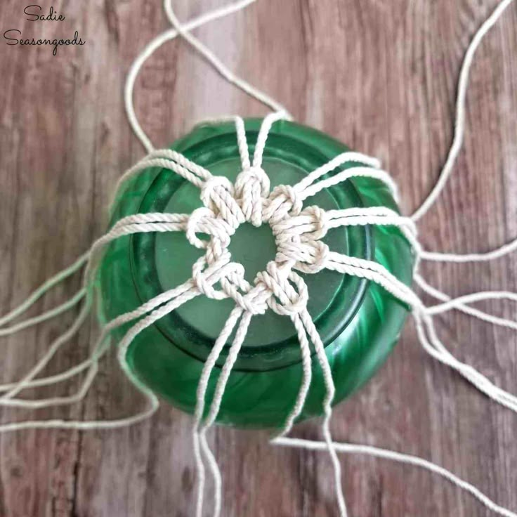 a green bottle sitting on top of a wooden table next to some white string and twine