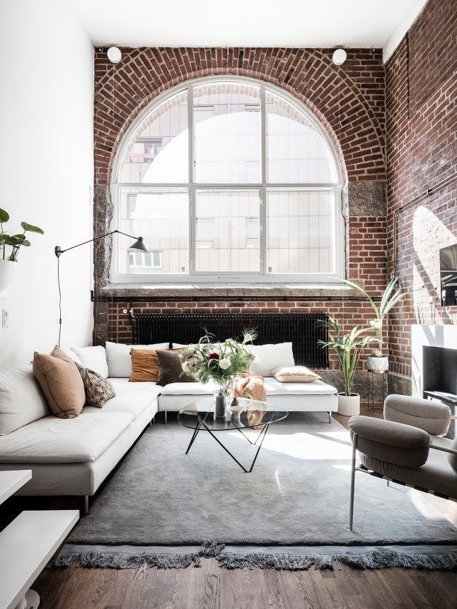 a living room filled with furniture and a large window in the wall above it's fireplace