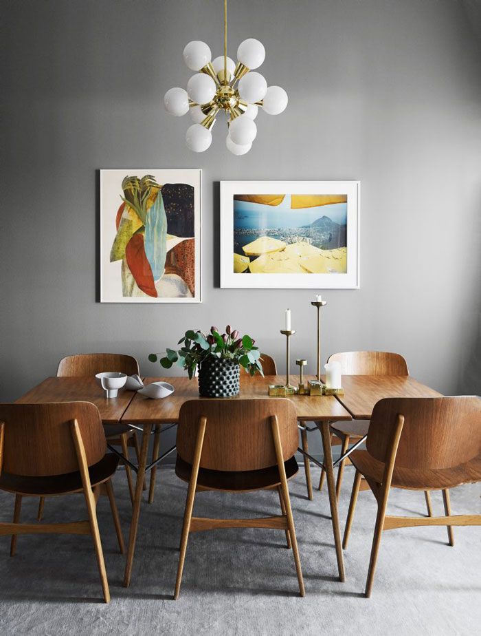 a dining room table with chairs and pictures on the wall above it, along with two paintings