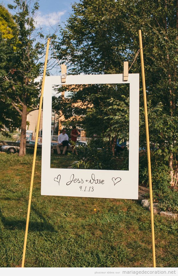 a white sign sitting on top of a lush green field next to a tree filled park