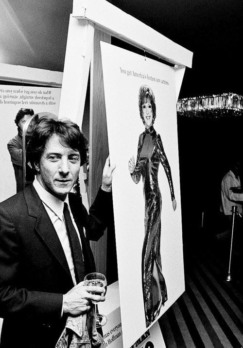 a man in a suit and tie standing next to an art piece with a woman on it