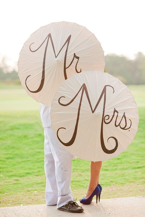 a man and woman holding umbrellas with the word mr and mrs written on them